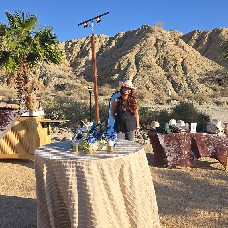 woman poses and smiles by a desert event activation and hat gifting station in Palm Springs
