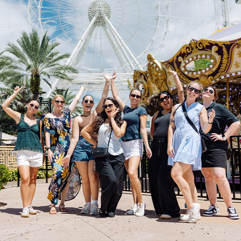A group of people posing in front of theme park rides