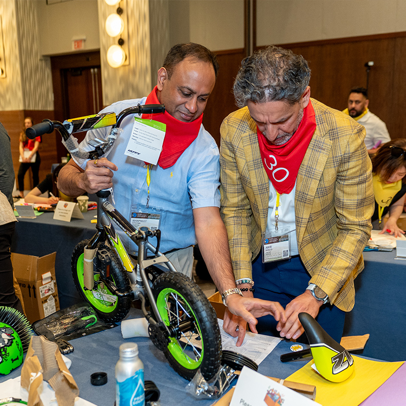 two men working together to assemble a small bicycle